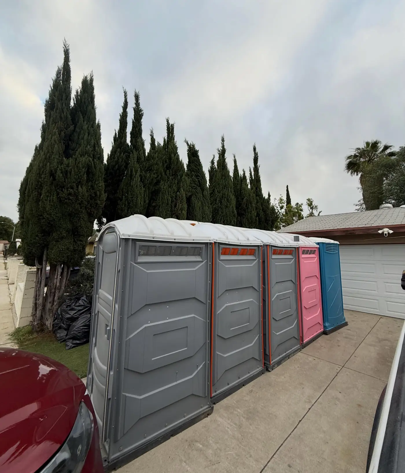 Gray porta potties along a backyard fence