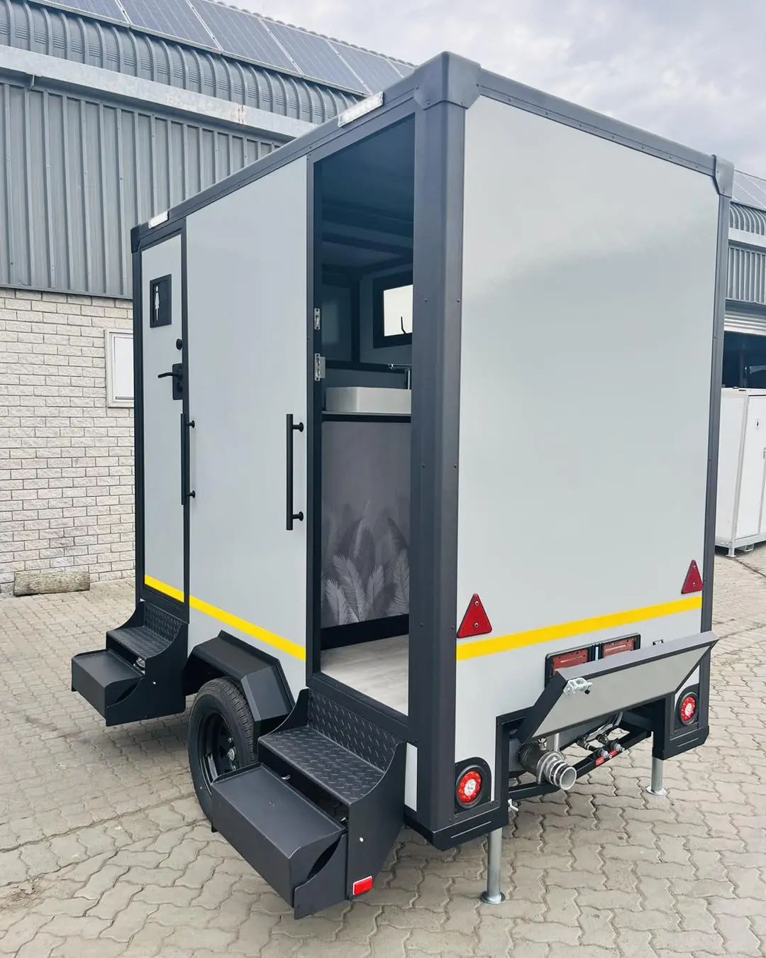 Rear view of a white two-station restroom trailer with fold-down steps