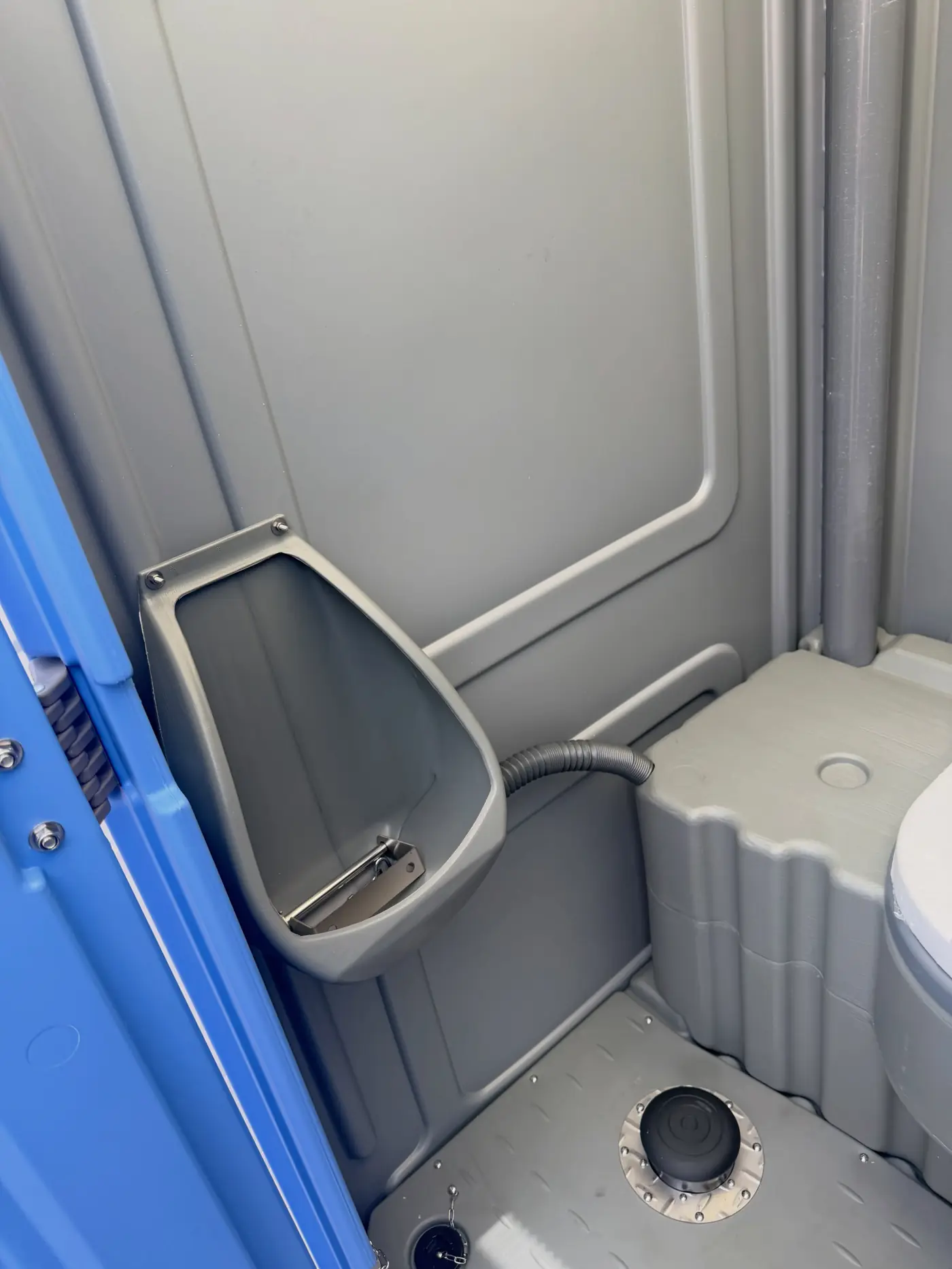 Close view of the urinal and sanitizer dispenser inside a standard porta potty