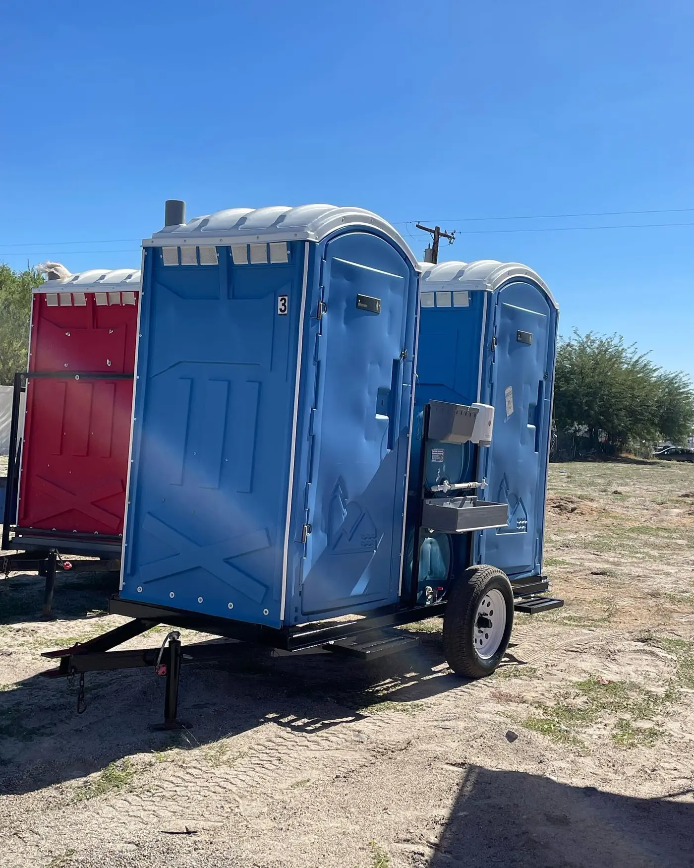 Trailer-mounted portable toilets on a gravel yard near Butler